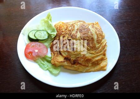 Nasi Goreng Pattaya ou connu comme omelette farcie de riz frit servi sur une plaque blanche sur table en bois Banque D'Images