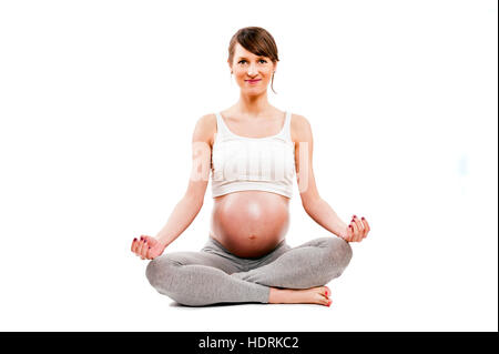 Méditant sur la maternité. Close-up of pregnant woman meditating while sitting in lotus position Banque D'Images