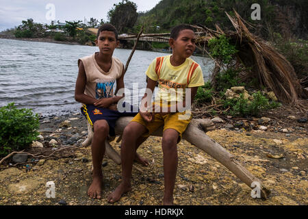 Deux jeunes garçons assis sur un tronc d'arbre dans la zone touchée par l'ouragan Mathew, Baracoa, Cuba Banque D'Images