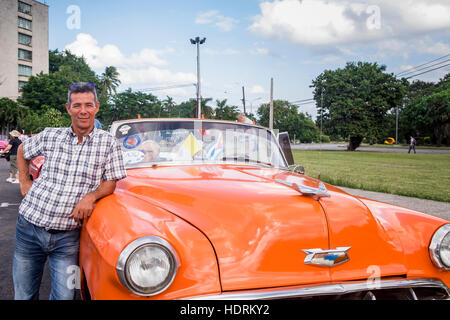 Chauffeur posant avec sa vieille voiture cabriolet américain des années 1950 sur la place de la Révolution, La Havane, Cuba. Banque D'Images