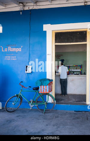 Boutique dans la ration, l'homme au comptoir de Vinales et location appuyé contre mur à l'extérieur, Cuba Banque D'Images