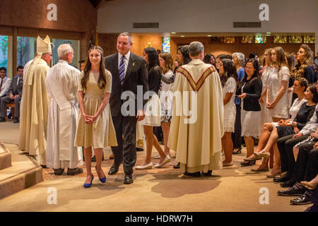 Habillé officiellement multiraciale adolescents et parents participent à la messe de confirmation à une Laguna Niguel, CA, l'église catholique. Remarque L'évêque Monseigneur et robe blanche et robe formelle. Banque D'Images