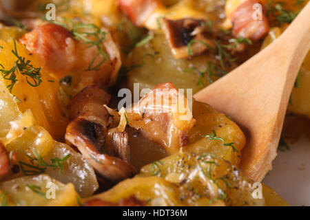 Pomme de terre au four avec bacon, champignons et fromage macro avec une cuillère en bois. Banque D'Images