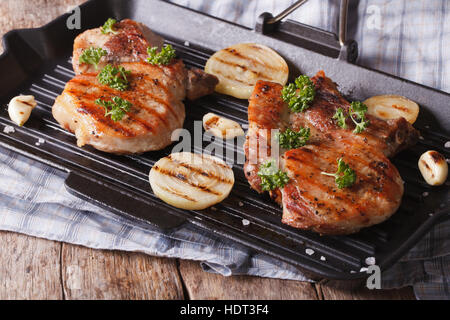 Deux steak de porc avec l'oignon dans une poêle grill sur la table horizontale de près. Banque D'Images