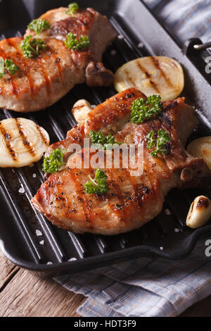 Deux steak de porc avec l'oignon dans une poêle grill sur la table close-up. La verticale Banque D'Images