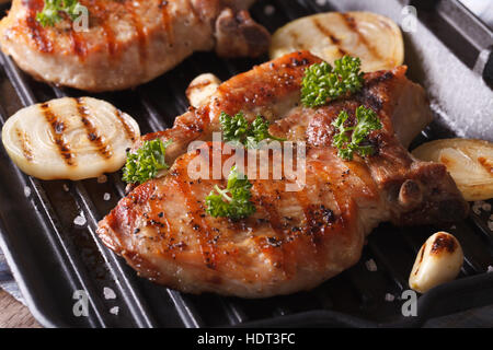 Deux escalope de porc grillée avec des oignons et l'ail dans une poêle grill libre horizontale. Banque D'Images