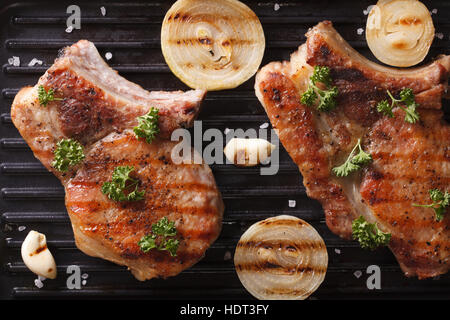 Deux steak de porc grillé juteux avec l'oignon et l'ail dans une poêle grill horizontal. Gros plan Vue de dessus Banque D'Images