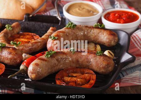 Cuisson : Hotdog de saucisses grillées, de légumes dans une poêle grill, les petits pains avec la sauce sur la table horizontale de près. Banque D'Images