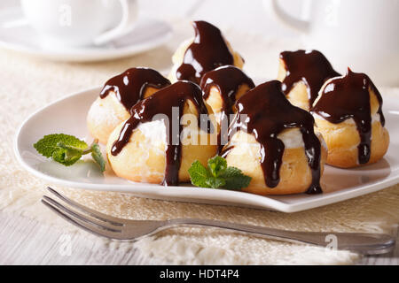 Éclairs délicieux glaçage au chocolat et à la crème sur une plaque horizontale. Banque D'Images