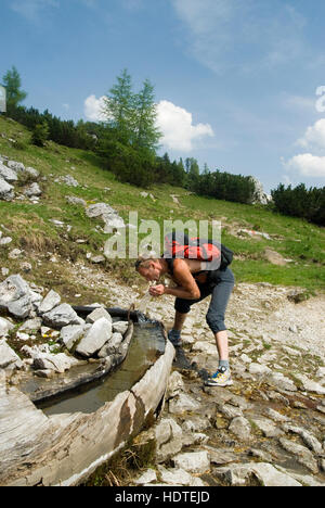 Randonneur boire d'une fontaine en bois, Admont, Styrie, Autriche, Europe Banque D'Images