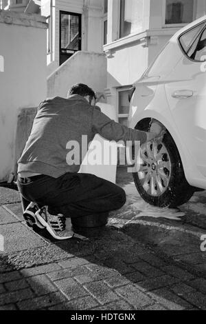 Un jeune homme voiture lavage à la main à l'aide d'un seau d'eau chaude england uk Banque D'Images