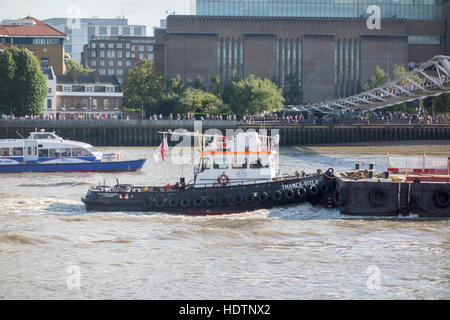 Remorqueur Bateau poussant une barge sous Millennium Bridge sur la Tamise, Londres, UK Banque D'Images
