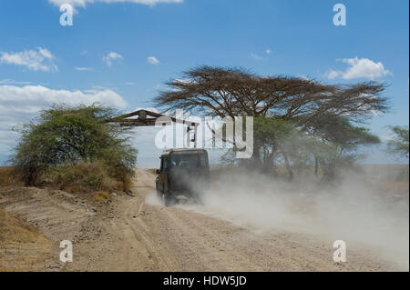 Jeep de la conduite sur route de gravier poussiéreux du Serengeti dans la Ngorongoro Conservation Area, Tanzania Banque D'Images