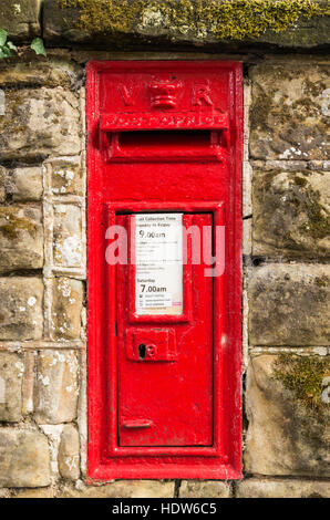 Et emblématique de l'ère victorienne traditionnelle lettre rouge Royal Mail postbox post box avec VR insérés dans un mur de briques. Banque D'Images