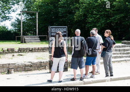 Lecture visiteurs un panneau d'information à proximité sur la potence où les prisonniers sont accrocher et aussi le commandant du camp d'Auschwitz Banque D'Images