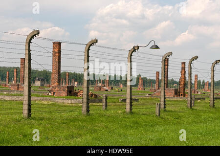 Les vestiges des cheminées qui faisaient partie de la prison derrière de hauts bâtiments barb wire clôtures à Auschwitz-Birkenau 11 à Oswiecim, Pologne, Banque D'Images