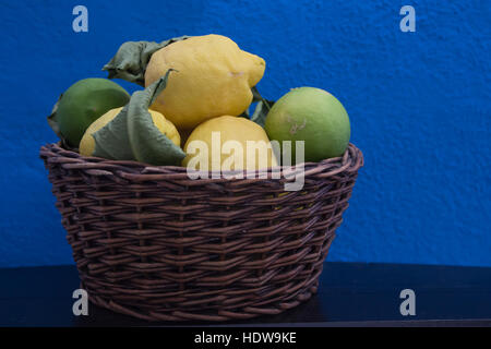 Citron frais dans un panier en osier sur un fond bleu Banque D'Images