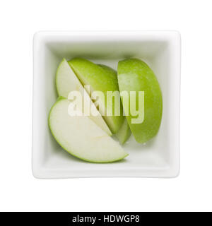 Tranches de pomme verte dans un bol carré isolé sur fond blanc Banque D'Images