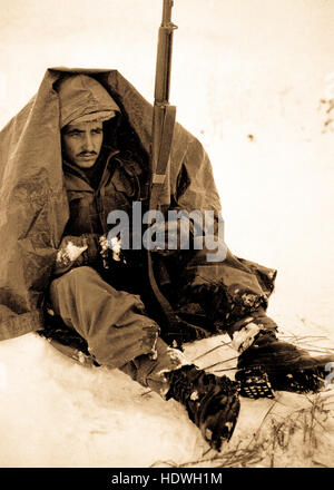 Le soldat de première classe Preston McKnight, 19e Régiment d'infanterie, utilise son poncho pour se protéger contre les morsures du vent et du froid, dans la région, au moment des pauses Yoju en action contre le Parti communiste chinois agresseurs. 10 janvier, 1951. Banque D'Images