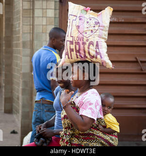 « J'aime l'Afrique » - une femme porte un sac avec inscription sur la tête et bébé sur le dos. L'optimisme et la joie de vivre règnent en Sierra Leone Banque D'Images