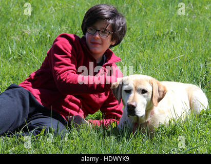 Garçon de race blanche aux cheveux longs noirs avec son chien labrador retriever Banque D'Images