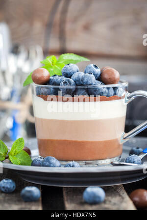 Trois délicieux dessert mousse au chocolat en couches, décorées avec de bleuets frais, de menthe et de bonbons, servi dans la tasse en verre Banque D'Images