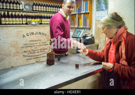 Une femme l'achat d'un shot de liqueur de cerises aigres, ginja, un bar Ginjinha, Largo de São Domingos, Lisbonne, Portugal Banque D'Images