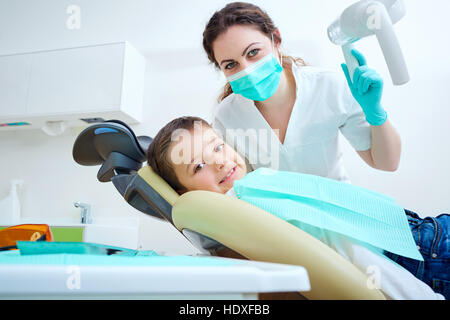 Bel enfant boy smiling in dentist's chair l'Office traite les dents. Masque de médecin et l'enfant examine l'appareil photo. Banque D'Images