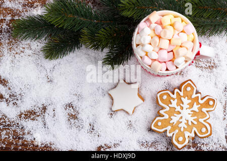 Chocolat chaud avec guimauves fondues en rouge tasse et pain d'épices cookies sur la neige. Vue de dessus avec copie espace Banque D'Images