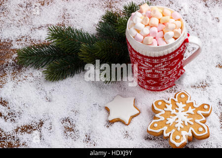 Chocolat chaud avec guimauves fondues en rouge tasse et pain d'épices cookies sur la neige. Vue de dessus avec copie espace Banque D'Images