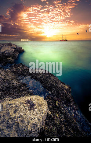 Fineart de atmosferic seascape, bateau en bois, avec le coucher du soleil, les mouettes et un petit crabe sur les rochers. Banque D'Images