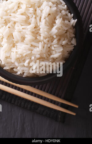 Délicieux dans un bol de riz noir macro et baguettes. vertical vue d'en haut Banque D'Images