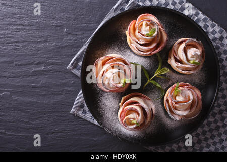 Belles pâtisseries : pommes cuites sous la forme de roses sur une plaque noire horizontale vue du dessus. Banque D'Images