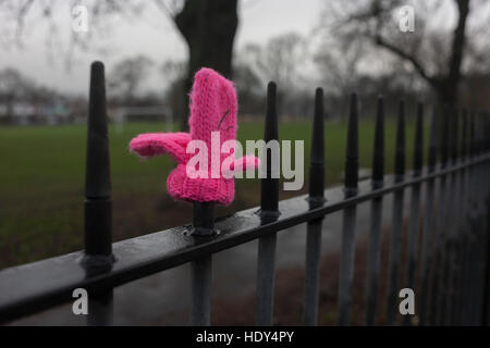 Un seul enfant rose moufle gauche sur Park garde-corps sur un jour d'hiver, le 15 décembre 2016, dans la région de Ruskin Park, Londres, Angleterre. Banque D'Images