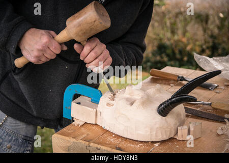 Ancien charpentier sculpte un masque de carnaval en bois. Banque D'Images