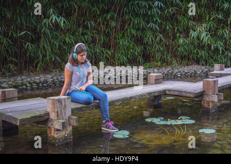 Fille à écouter la musique au casque dans le parc Banque D'Images