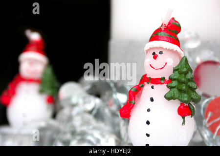 SNOWMAN : bonhomme habillé en écharpe et hat carrying Christmas Tree candle Banque D'Images