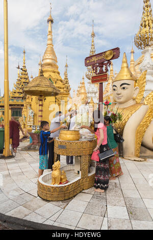 Les gens verser de l'eau sur une statue de Bouddha, Shwedagon pagoda, Yangon, Myanmar Banque D'Images