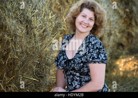 Femme souriante dans le champ sur fond de bottes de paille Banque D'Images