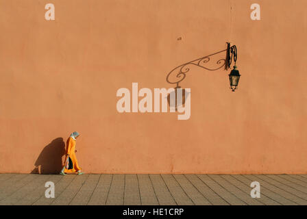Jeune femme en costume traditionnel en passant par les murs de la ville de Marrakech, Marrakech, Maroc, Afrique Banque D'Images