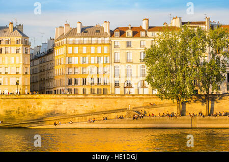 Les personnes bénéficiant de coucher du soleil sur les bords de Seine, quai d'Orléans, quartier ile Saint Louis Banque D'Images