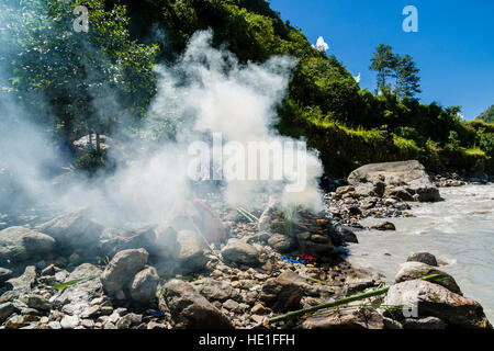 Le feu de l'enterrement d'un corps mort à la crémation la masse sur la rive de la rivière Kali Gandaki produit beaucoup de smok Banque D'Images