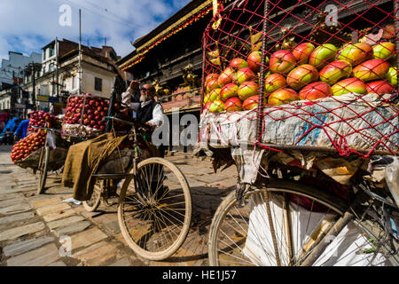 Les vendeurs de fruits, à l'aide de vélos, offrent des pommes et des oranges sur indra chowk en face de temple akash bhairab Banque D'Images