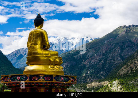 Une statue du Bouddha d'or est situé sur une base de pierre, face à la vallée de l'upper marsyangdi Banque D'Images