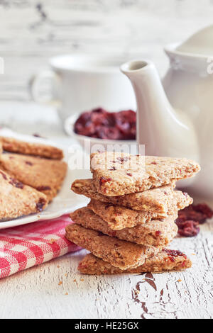 Pile de biscuits de blé entier avec des canneberges sur fond blanc en bois rustique Banque D'Images