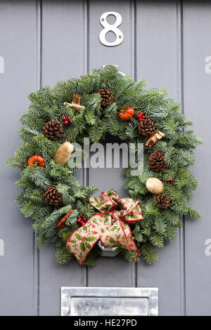 Couronne de noël décoratif suspendu par une porte avant gris. Banque D'Images