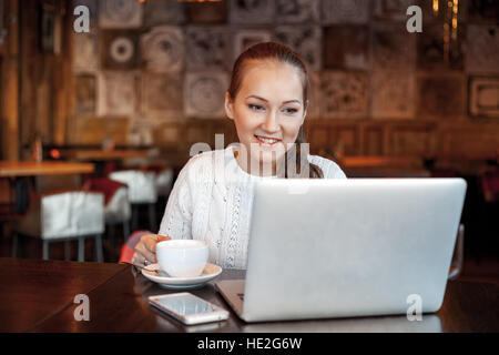 Yong femme un travail à laptop in cafe Banque D'Images