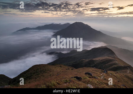Nuages roulant sur une montagne sur l'île de Lantau, vu depuis le pic de Lantau (le 2e plus haut sommet de Hong Kong, Chine), à l'aube. Banque D'Images