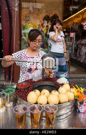 Hui uyghur woman preparing food dans le quartier musulman de Xian, Chine marché. Banque D'Images