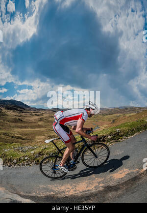 Un homme escalade Hardknott Pass cycliste dans le Lake District, UK. Logo ont été supprimés. Banque D'Images